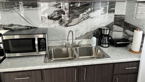 A modern kitchen with a stainless steel microwave, double sink, and coffee maker. - Villa Carmin 2 with Private Pool (Aguadilla)