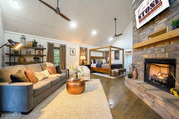 A spacious living room with a fireplace, a sofa, a coffee table, and a bed with a canopy.