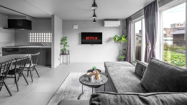 A modern living room with a grey sofa, a coffee table, and a TV mounted on the wall. - SNOWGARDEN YIG STAY (Furano)