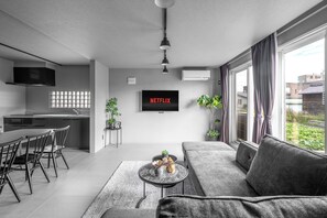 Un salon moderne avec un canapé gris, une table basse et un téléviseur fixé au mur.