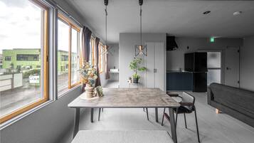 A modern living room with a dining table, sofa, and kitchen area.