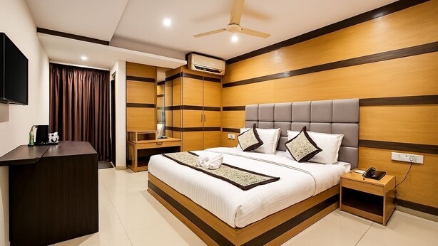 A modern hotel room with a large bed, bedside tables, a desk, and a ceiling fan.