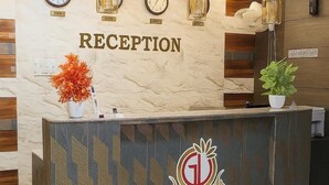 A reception desk with a marble wall, clocks, and pendant lights.