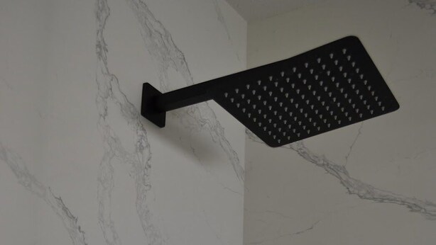 Ein an der Wand befestigter Duschkopf mit Marmoroptik.