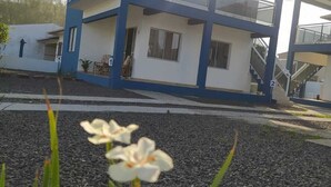 A two-story building with a balcony, a staircase, and a small garden area with flowers.