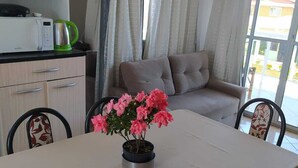 A dining area with a table, chairs, a potted plant, and a sofa.