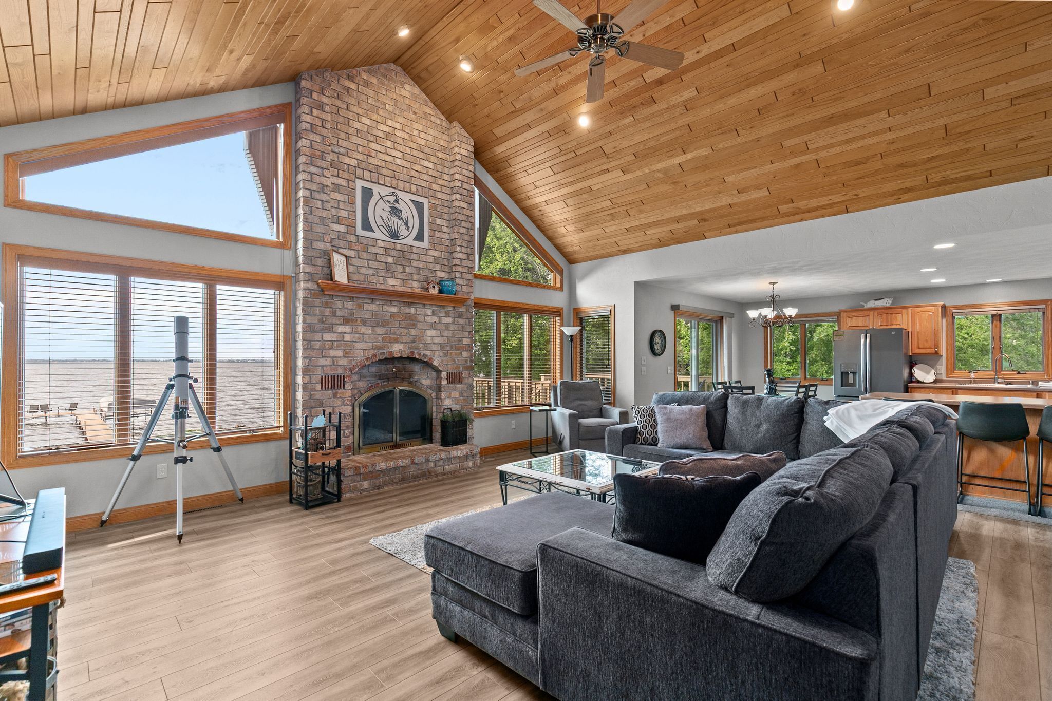 A spacious living room with a fireplace, large windows, and a modern kitchen.