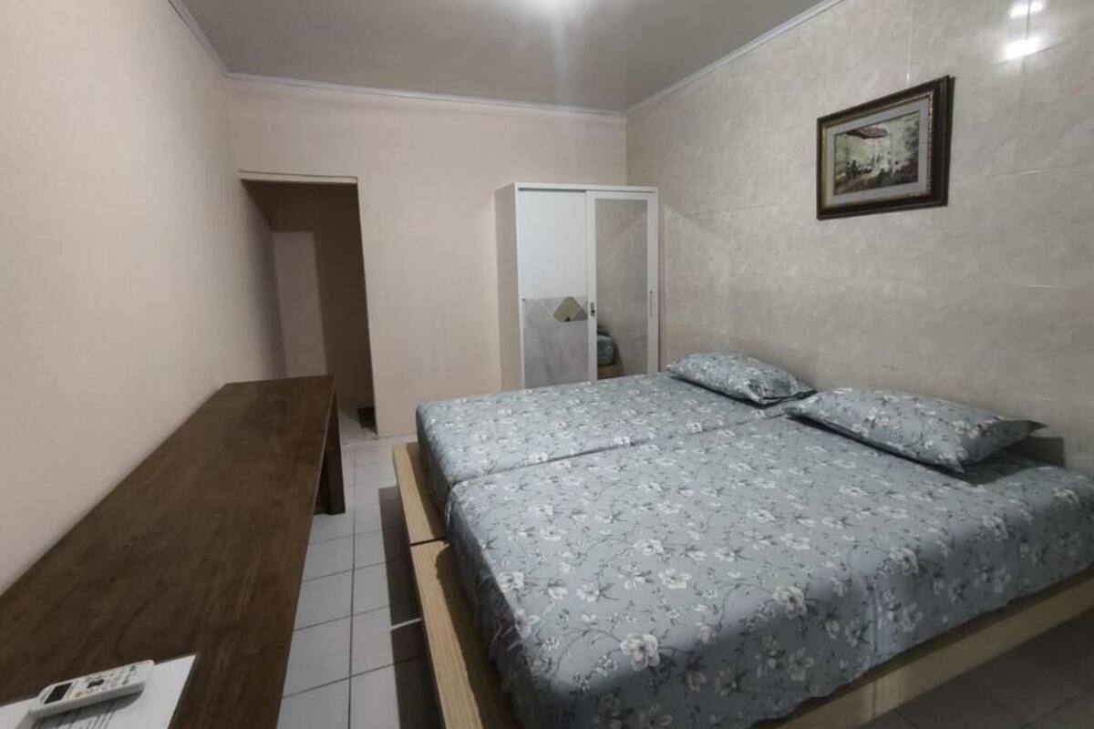 A bedroom with a bed, a wooden desk, and a wardrobe.