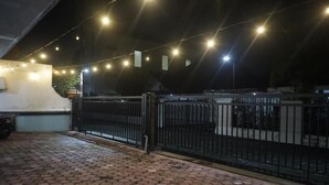 Un espacio al aire libre con suelo pavimentado, cerca de metal negro y luces colgantes.