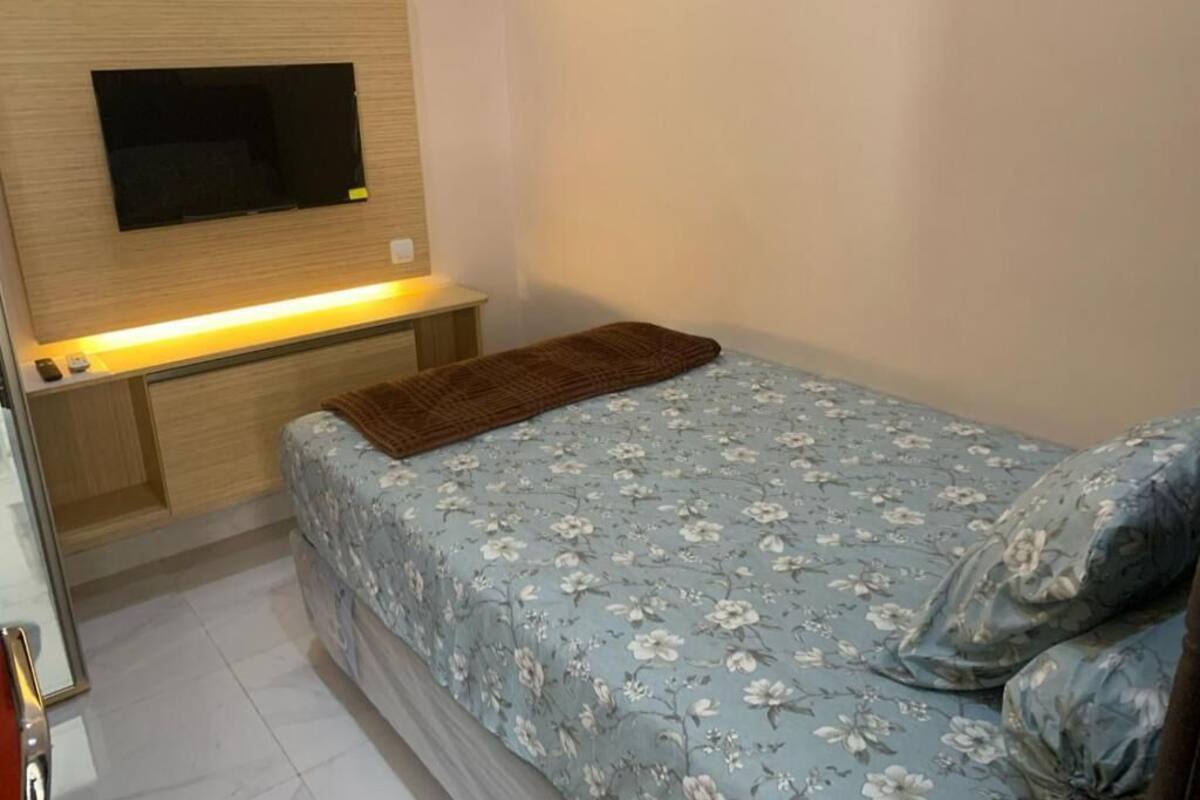 A bedroom with a bed, a TV mounted on the wall, and a bedside table.