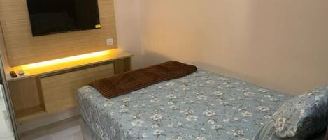 Une chambre à coucher avec un lit, un téléviseur fixé au mur et une table de chevet.