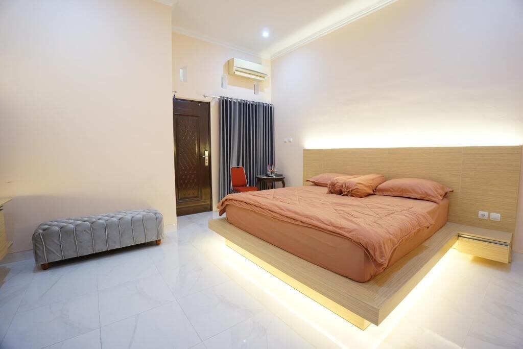 A modern bedroom with a large bed, a bench, and a small table.