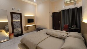 Una habitación de hotel moderna con una cama grande, un televisor fijado a la pared, un escritorio pequeño y una puerta corrediza.