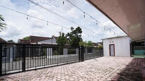 Un patio empedrado con un diseño de mosaicos hexagonales, una cerca de metal negro y un edificio blanco con una puerta.