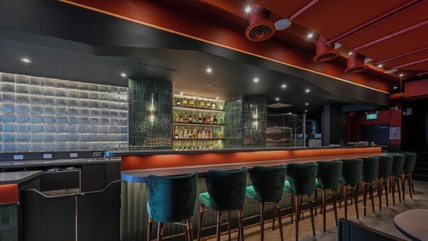 A bar area with a counter, bar stools, and a shelf with bottles. - Nomas Hotel (Toronto)