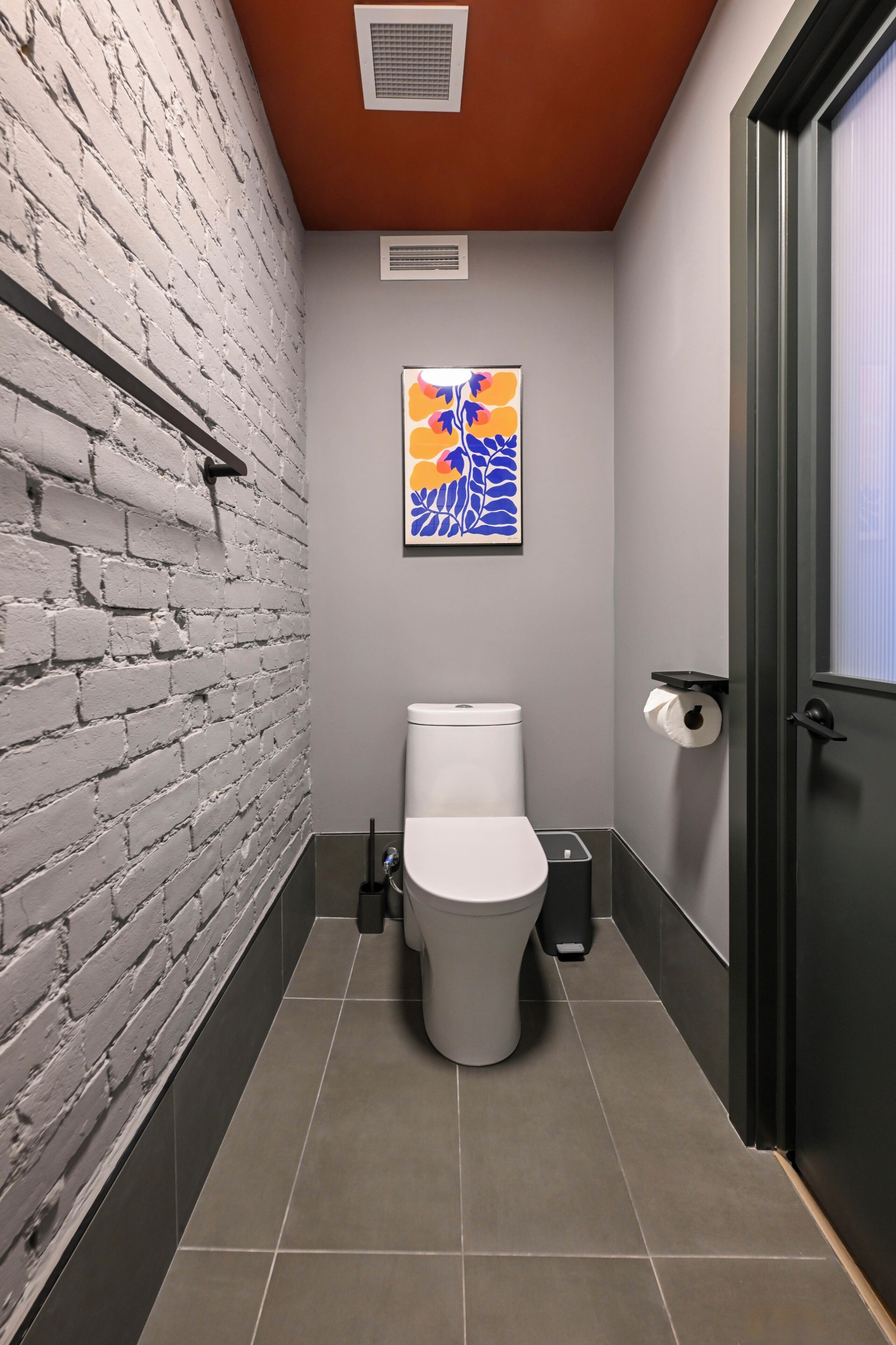 A modern bathroom with a white brick wall, a toilet, a sink, and a shower.