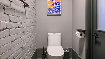 A modern bathroom with a white brick wall, a toilet, a sink, and a shower.