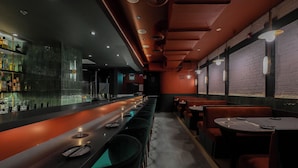 A bar area with a long counter, stools, and tables. - Nomas Hotel (Toronto)