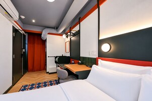 Een hotelkamer met een bed, bureau, stoel en een badkamer met douche.