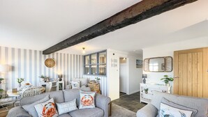 A living room with a grey sofa set, striped wall, and a wooden ceiling beam.