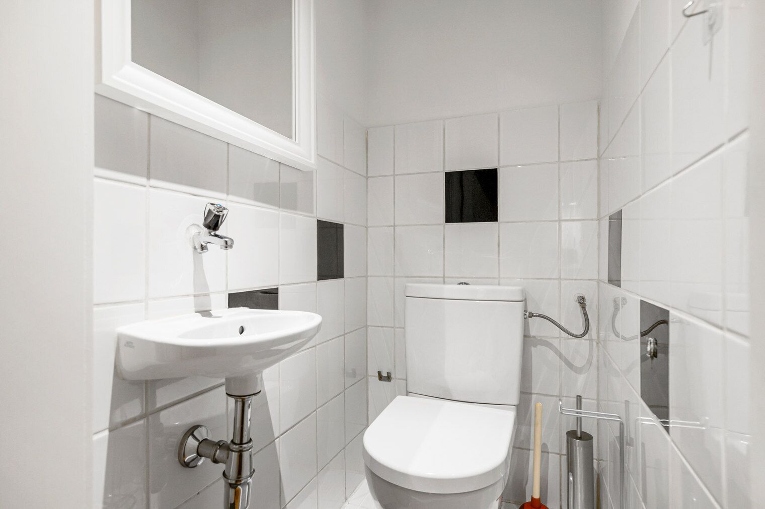 Une salle de bain moderne avec un lavabo blanc, des toilettes et un miroir au-dessus du lavabo.