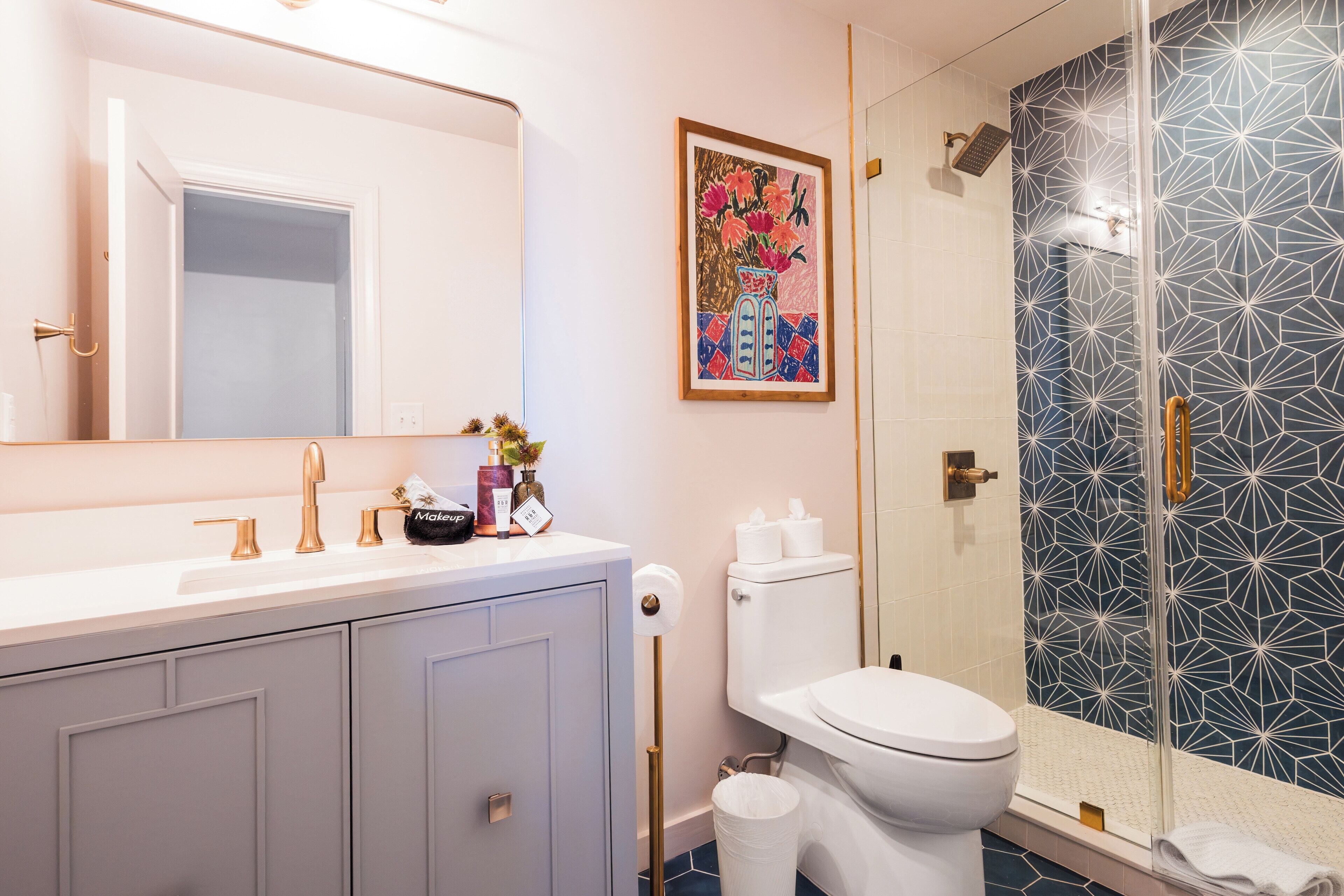 A bathroom with a white sink, a toilet, and a shower with a geometric tile pattern.