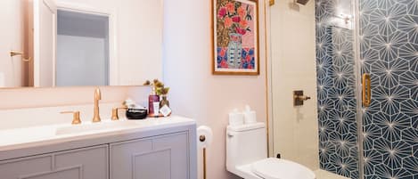 A bathroom with a white sink, a toilet, and a shower with a geometric tile pattern.
