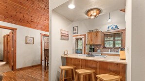 Una cocina con armarios de madera, una barra y taburetes.