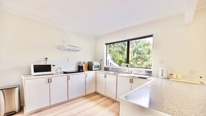 A modern kitchen with white cabinets, a microwave, a stove, and a sink. - Tamarillo Bach - Your Relaxing Beach Escape in Coopers Beach (Coopers Beach)