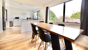 A modern kitchen with white cabinets, a wooden dining table, and black chairs. - Tamarillo Bach - Your Relaxing Beach Escape in Coopers Beach (Coopers Beach)