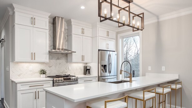 A modern kitchen with white cabinetry, stainless steel appliances, and a large island with bar stools.