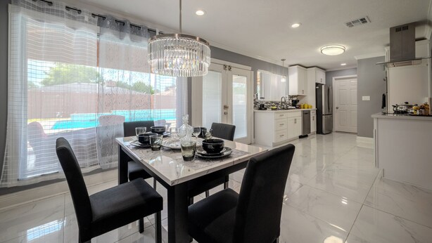 A modern kitchen with white cabinets, a central island, and a dining area with a table set for four. - Spacious 4-bedroom house in awesome Houston (Houston)