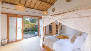 Un dormitorio con cama a dosel, vistas al jardín y techo de paja.
