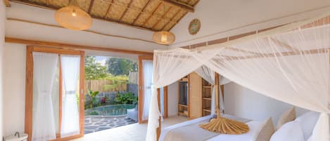 A bedroom with a canopy bed, a view of the garden, and a thatched ceiling.