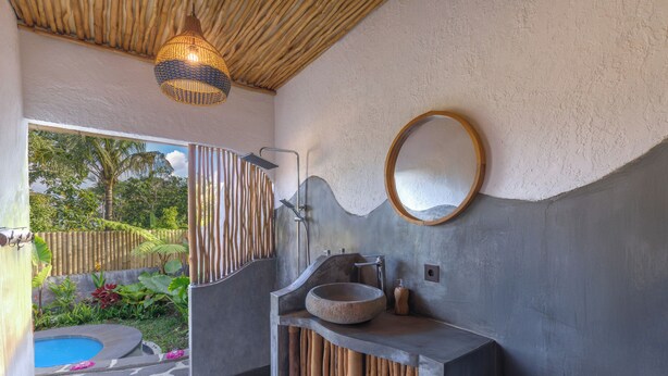 Un baño moderno con un lavabo de piedra, un espejo grande y un diseño de panel de madera único.