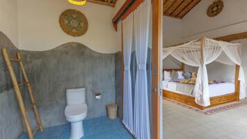 Casa de banho com sanita, uma escada de madeira e zona de duche com cortina branca.