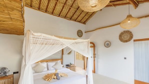 Un dormitorio con cama a dosel, cabecero de madera, mesitas de noche y lámpara de techo tejida.