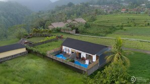 Una casa con piscina, rodeada de exuberante vegetación y un paisaje montañoso.