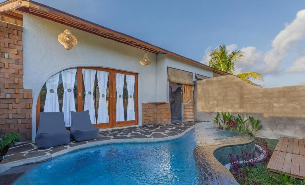 A pool area with a curved edge, a brick wall, and a covered entrance with curtains.