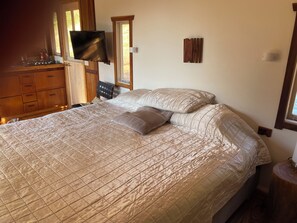 Une chambre à coucher avec un lit, une commode en bois et un téléviseur à écran plat fixé au mur.