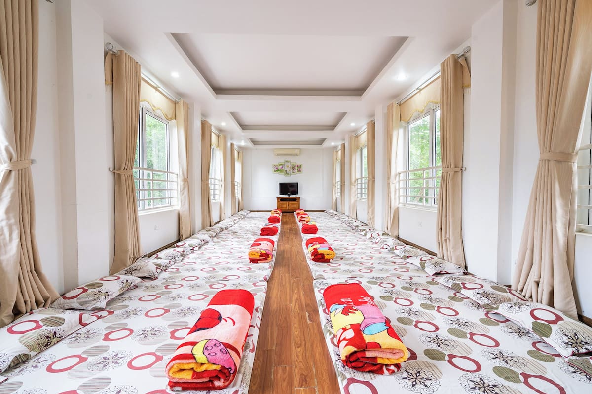 Habitación de hotel con un suelo de madera y una cama con colcha estampada, además de cortinas en las ventanas.