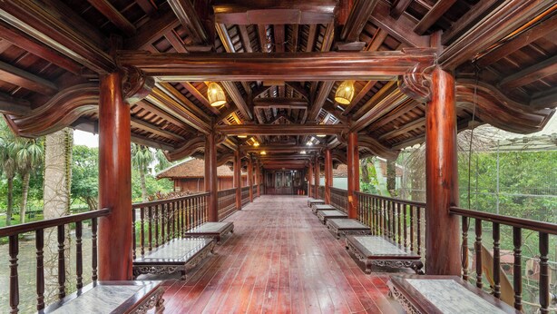 A wooden corridor with a polished floor, columns, and railings.