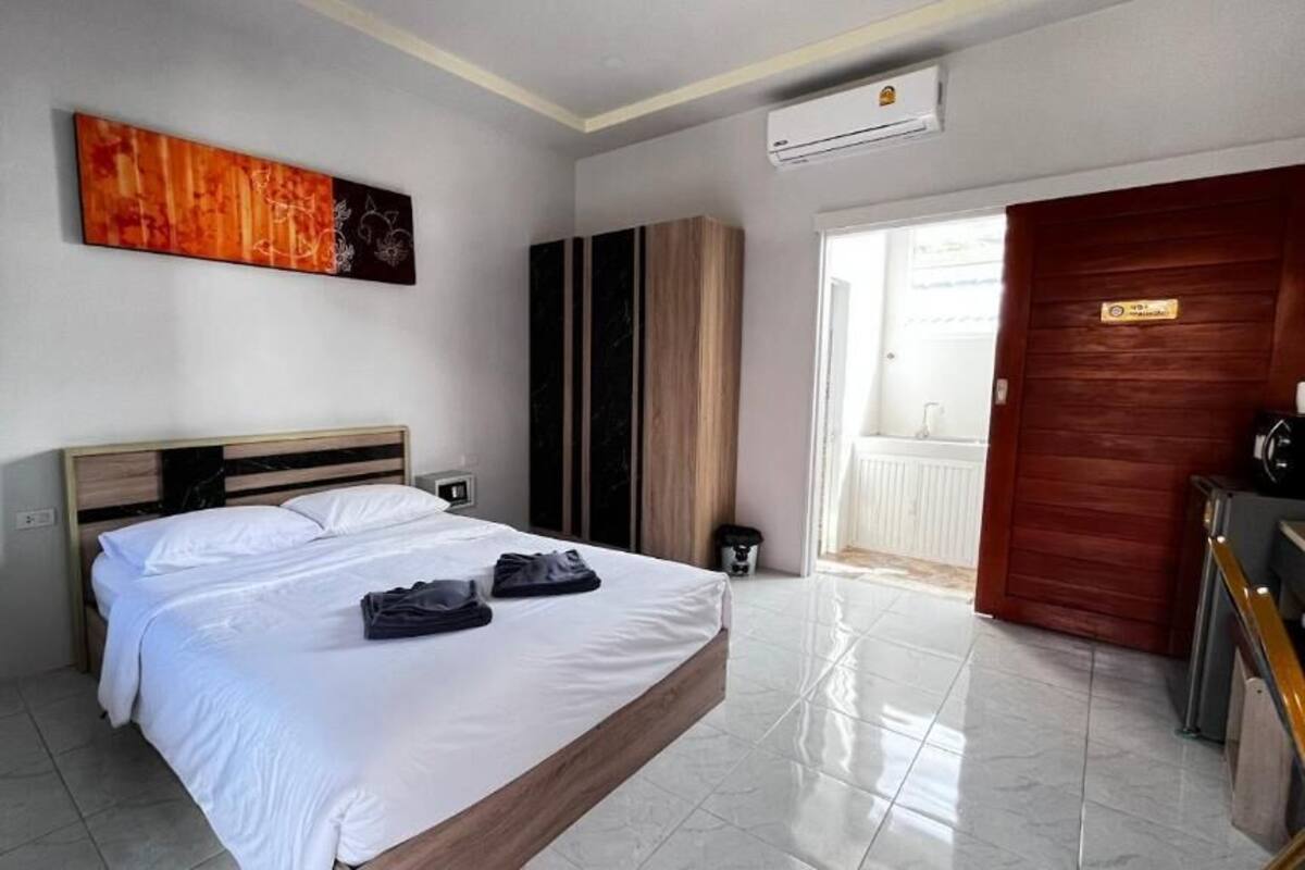 A hotel room with a bed, a painting, a wardrobe, and a door leading to a balcony.