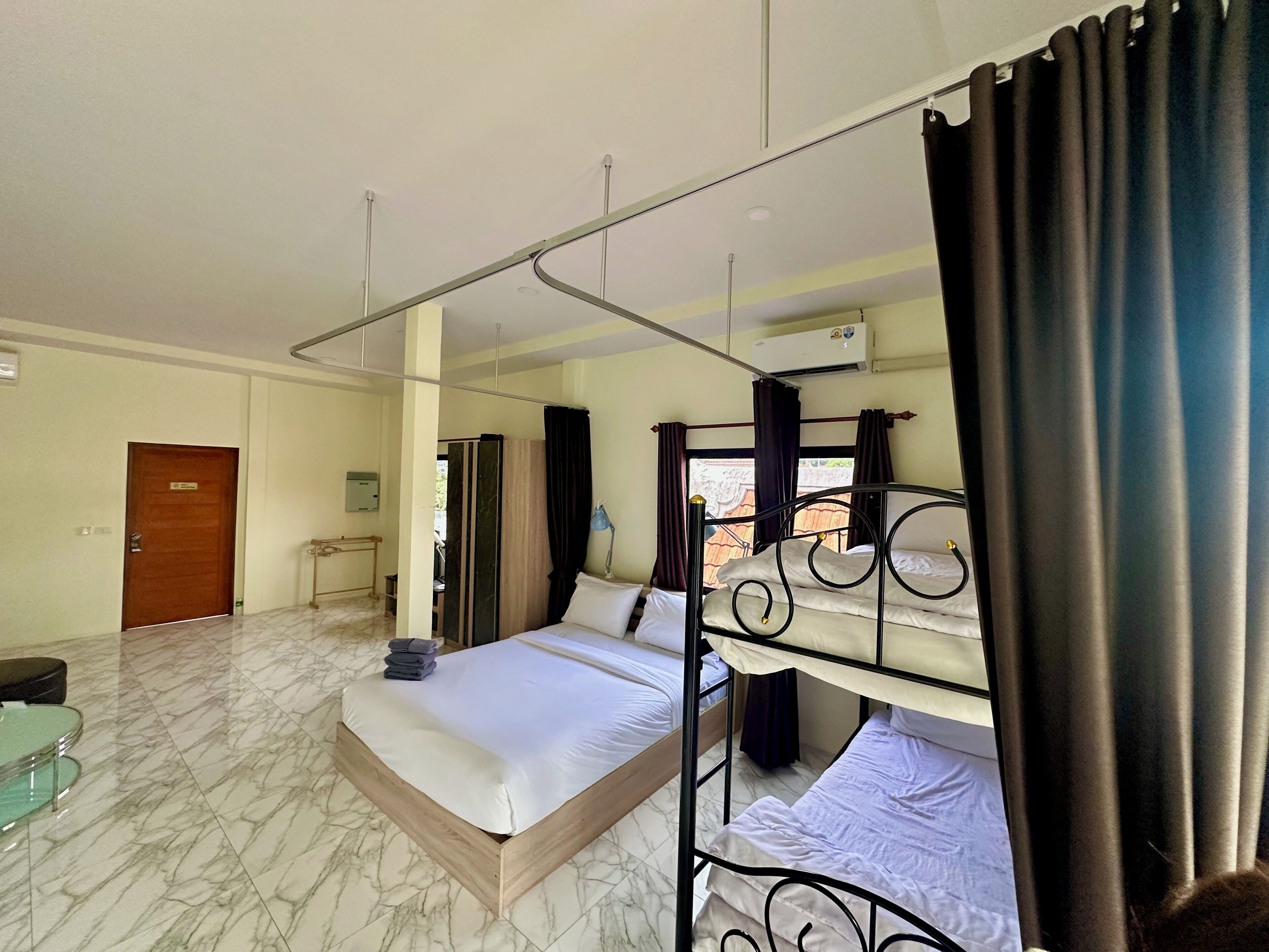 Une chambre d’hôtel comprenant un grand lit, un lit plus petit, un bureau et un espace salle de bain.