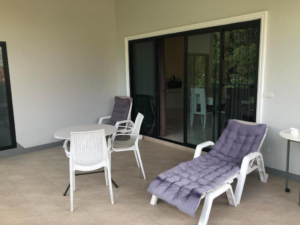 A balcony with a table, two chairs, and a single sun lounger.