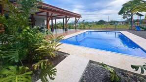 A swimming pool with a covered area and tropical plants.