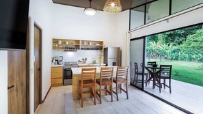 A modern kitchen with wooden cabinets, a central island, and a dining area with chairs. - Morpho Villas del Bosque at La Fortuna (La Fortuna, San Carlos)