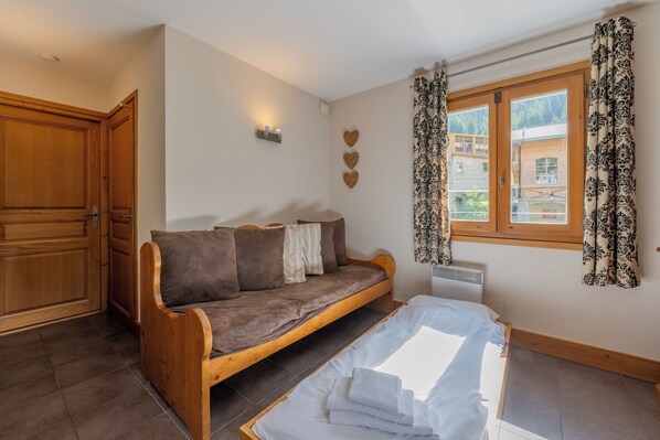 Ein Zimmer mit einem hölzernen Bett, einem Sofa, einem Kleiderschrank und einem fenster mit Vorhängen.