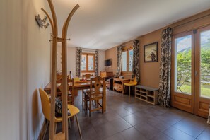 A dining area with wooden furniture, a TV, and a view of greenery outside. - Vallorcine Balme 06 Ski In / Ski Out, Vallorcine (Argentiere), France (Vallorcine (Argentiere))