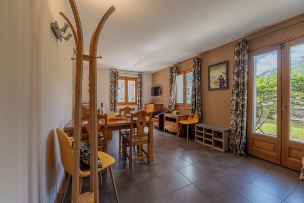 A dining area with wooden furniture, a TV, and a view of greenery outside. - Vallorcine Balme 06 Ski In / Ski Out, Vallorcine (Argentiere), France (Vallorcine (Argentiere))